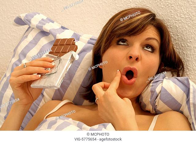 Eine junge Frau isst Schokolade im Bett, 2006 - Hamburg, Germany, 26/01/2006
