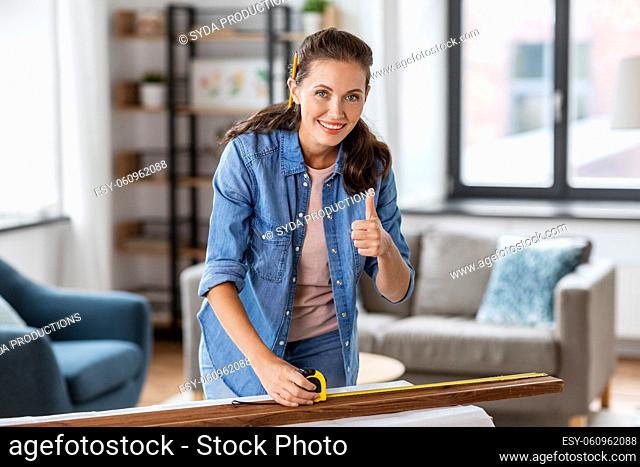 happy woman measuring board and showing thumbs up