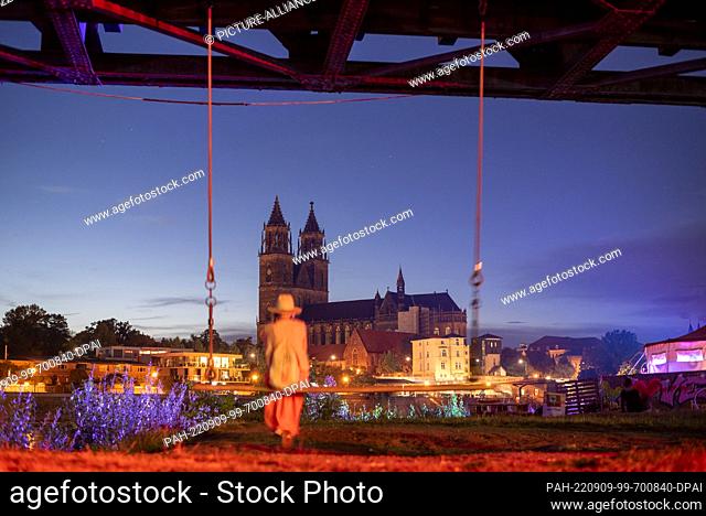 09 September 2022, Saxony-Anhalt, Magdeburg: A woman swings on the Elbe with a view of Magdeburg Cathedral. The three-day Kulturbrücke festival began this...