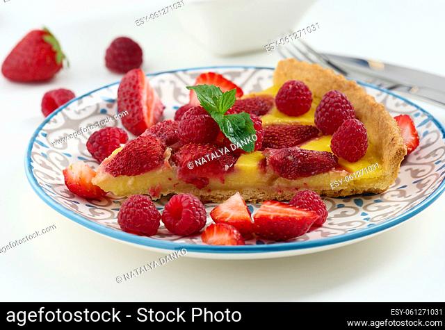 Round quiche with red strawberries and raspberries on a white table, top view