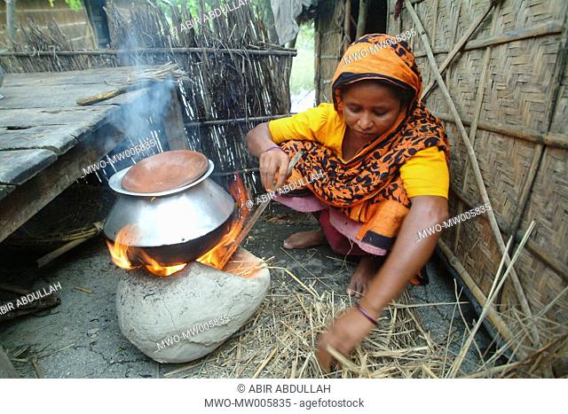 A rural woman cooking rice on an earthen oven in the flood affected area Gaibandha, Bangladesh July 21, 2004