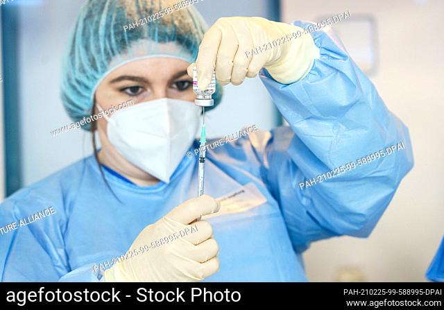 25 February 2021, Rhineland-Palatinate, Mainz: A pharmacist draws up AstraZeneca vaccine at a police vaccination center at the vaccination launch against the...