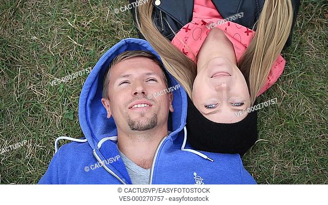 Sweethearts students lying on grass head to head