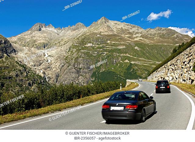Cars driving on the Furka Pass, the almost ice-free bed of the Rhone Glacier on the left, Belvédère Hotel in the centre, Gletsch, canton of Valais, Switzerland