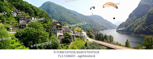 Para gliders over the rustic alpine village of Vogorno with paragliders over lake Vogorno, Val Verzasca, Tocino Switzerland