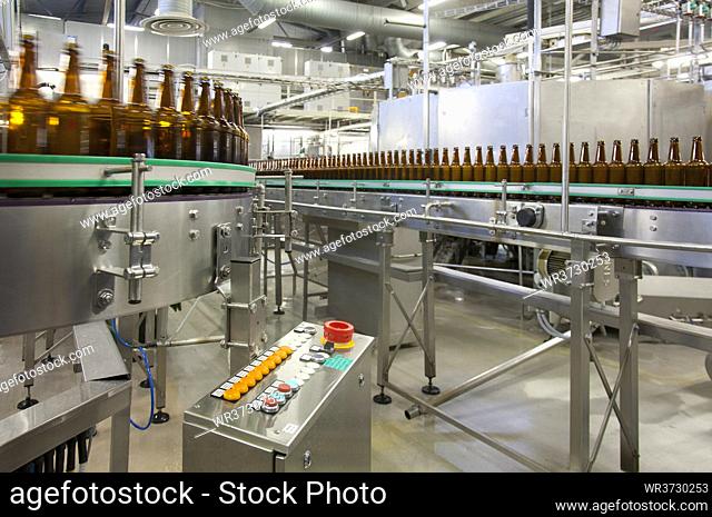 Beer bottling plant with moving belts, rows of bottles, automated process, capping and labelling and placing in crates