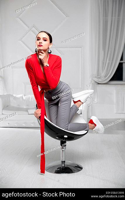 Pretty woman wearing a a red blouse and jeans posing in the studio