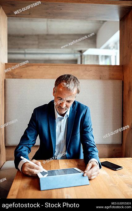 Senior male entrepreneur working on digital tablet at office