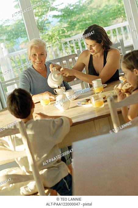 Grandmother, mother and children having breakfast