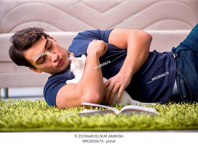 Young handsome man playing with white kitten