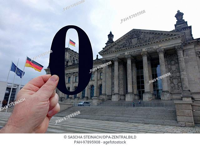 24.11.2017, Tiergarten, Platz der Republik, Berlin, Germany. A hand holding a black zero outside the Reichstag building. | usage worldwide