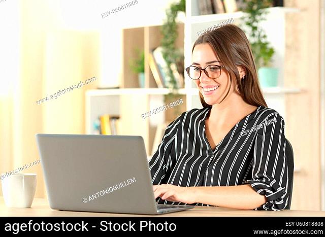Elegant woman wearing eyeglasses using laptop on a desk at home