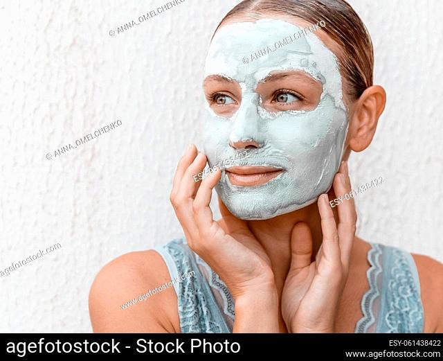 Closeup Portrait of a Pretty Girl with Cream Mask on her Face Isolated on White Background. Using Clay for Perfect Skin. Beauty Treatment Concept