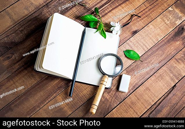 Photo of blank notebook, magnifier, pencil and eraser on wood table background