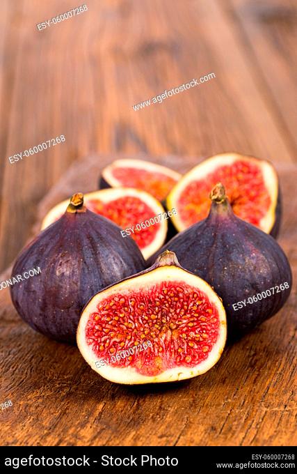 Group of whole and sliced ripe, delicious and sweets figs on a old rustic wooden cutting board