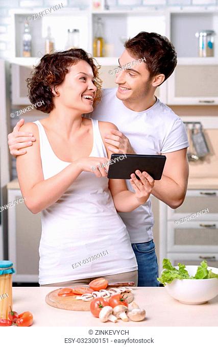 Have fun. Pleasant vivacious loving couple cooking and looking at each other while expressing positivity