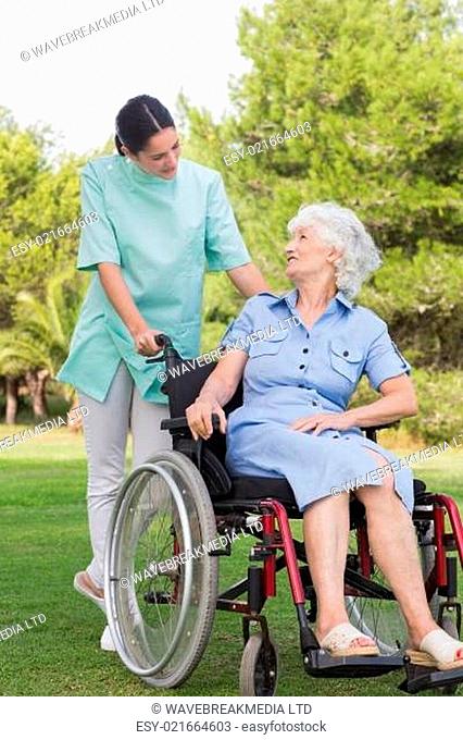 Nurse chatting with an elderly woman in wheelchair in the park