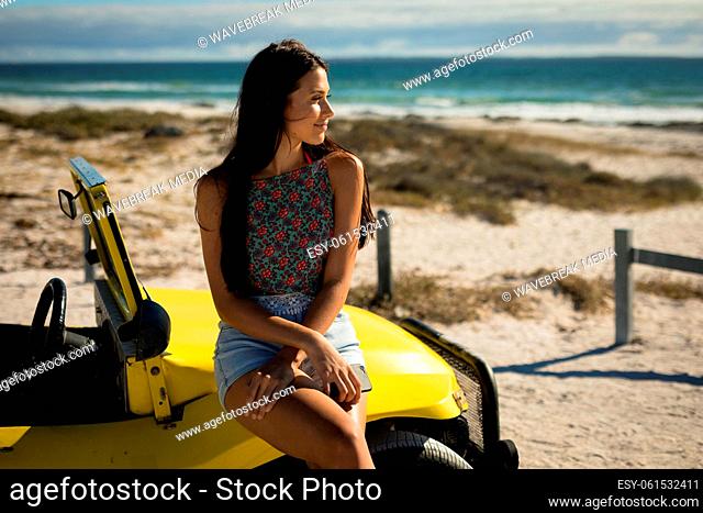 Happy caucasian woman sitting on beach buggy by the sea looking toward sea