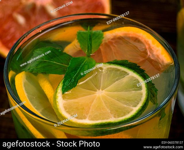 Close up cold homemade lemonade with fresh lemon, lime, grapefruit and mint. Summer drink on dark wooden background