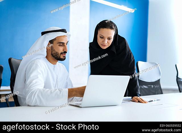 Man and woman with traditional clothes working in a business office of Dubai. Portraits of successful entrepreneurs businessman and businesswoman in formal...