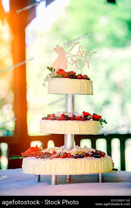 White wedding cake with flowers, strawberries, blueberries, raspberries and cranberries