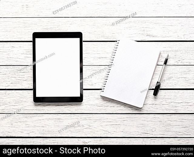 Tablet computer with notepad on white wooden desk. Clipping path included