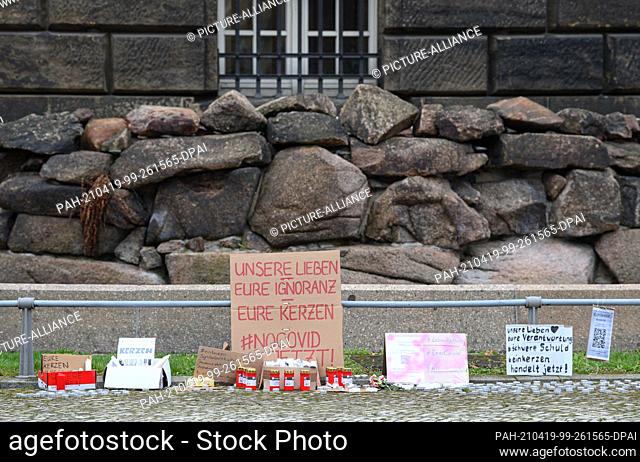 19 April 2021, Saxony, Dresden: Posters ""Our lives your ignorance your candles"" and candles are placed in front of the state chancellery