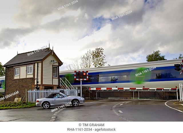 Car waits at railway crossing in Ascott-Under-Wychwood, Oxfordshire, United Kingdom