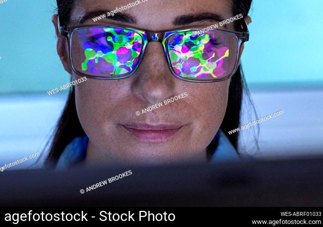 Reflection of molecular structure on scientist's eyeglasses in laboratory