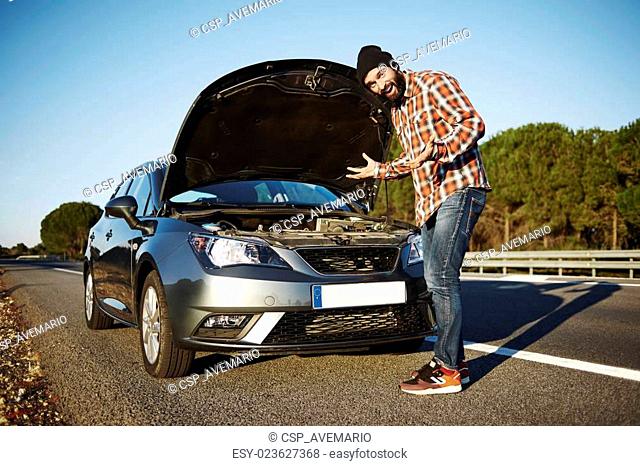 Car owner - young man puzzled breaking car and male surprised about this tragedy. Sad model standing beside broken car and threw up his hands