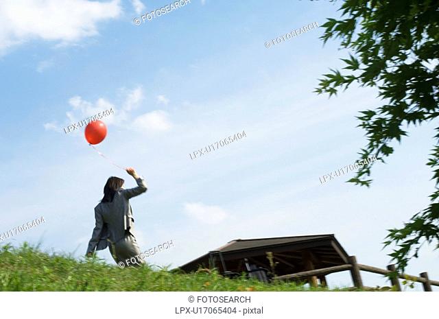 Businesswoman running with a balloon