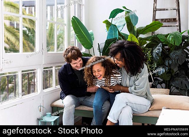 Happy family sitting in winter garden laughing and having fun