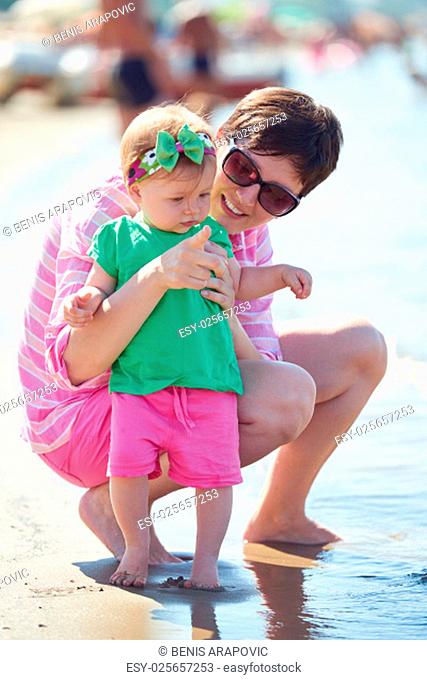 happy mom and baby on beach have fun while learning to walk and make first steps