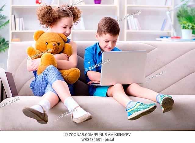 Two kids sitting at laptop at home