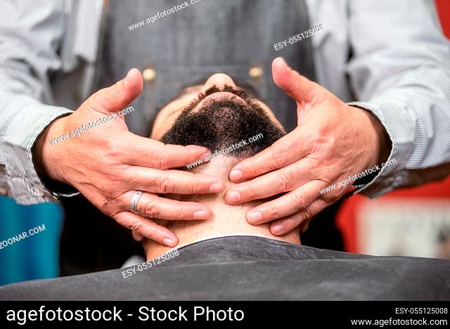 Hair stylist applying after shaving lotion at barber shop