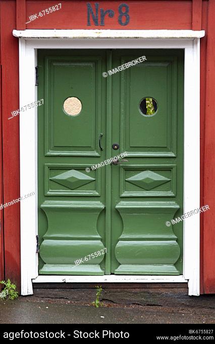 Traditional green wooden door with ornaments in red wooden house in Vimmerby, Kalmar Län, Smaland, Sweden, Europe