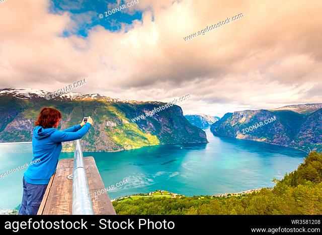 Tourism vacation and travel. Woman tourist taking photo with camera, enjoying Aurland fjord view from Stegastein viewpoint, Norway Scandinavia