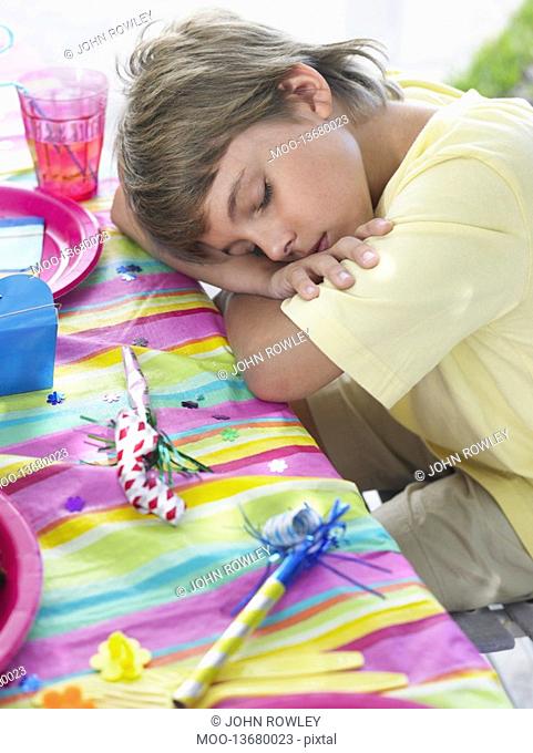 Close-up of boy 7-9 sleeping at table after birthday party