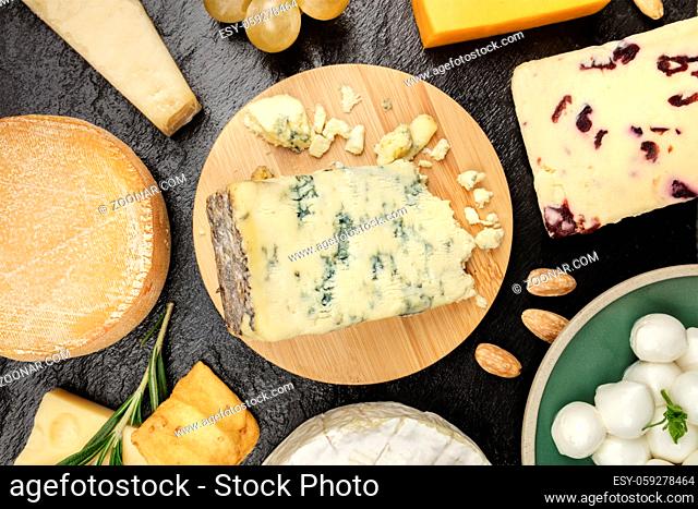 An assortment of various types of cheese, shot from above on a black background texture
