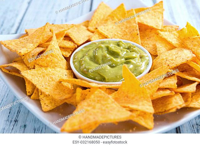 Nachos with Guacamole (close-up shot) on wooden background