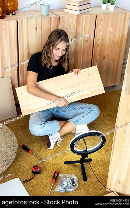 Smiling female influencer holding plank while vlogging at home
