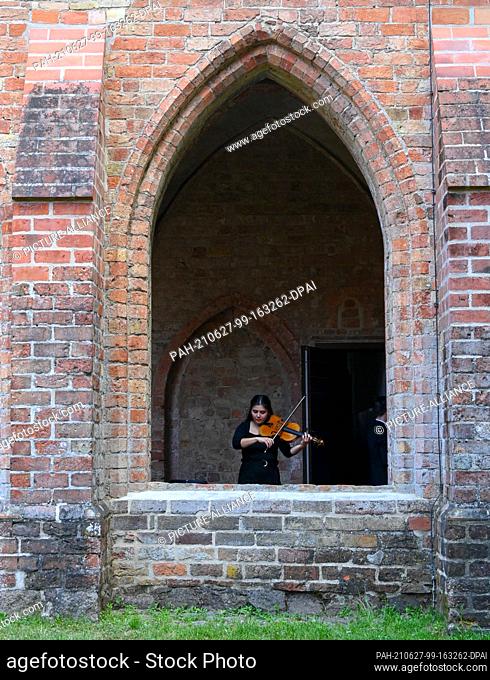 27 June 2021, Brandenburg, Chorin: A musician from the Mendelssohn Chamber Orchestra Leipzig tunes her instrument before the concert at Chorin Monastery during...