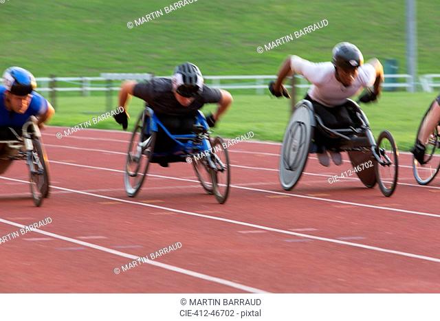 Determined paraplegic athlete speeding along sports track in wheelchair race