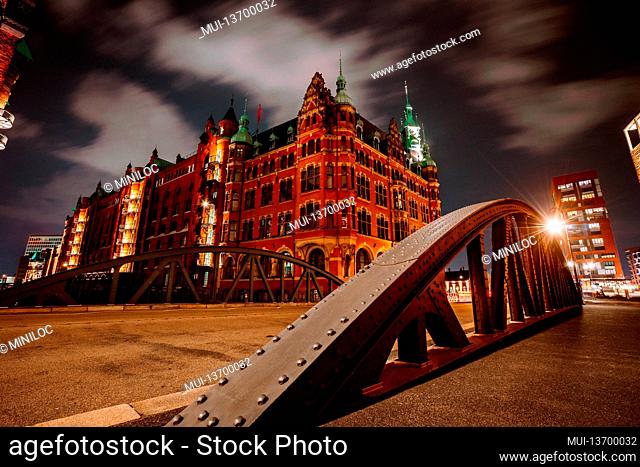 Old Speicherstadt in Hamburg illuminated at night. Arch bridge and historical buildings. Warehouse District -Speicherstadt Landmark of HafenCity quarter