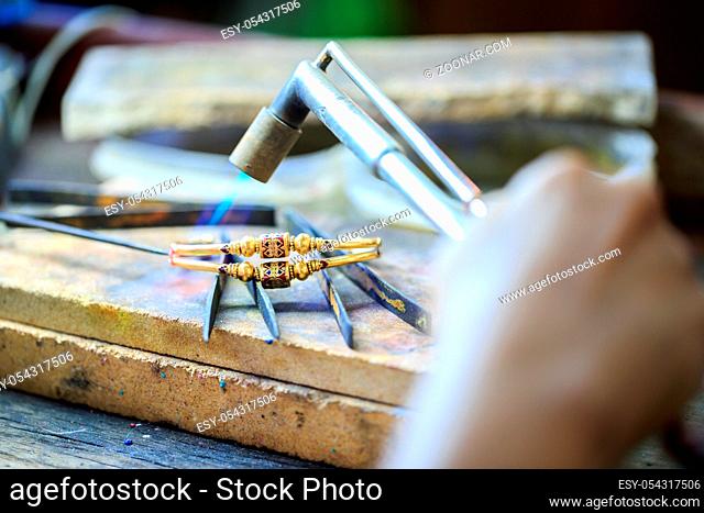Goldsmith working with a thai traditional bracelet