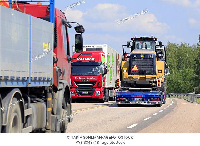 Orivesi, Finland. June 6, 2019. Freight transport by road with semi trailer hauling Cat wheel loader, refrigerated transport truck and truck with crane