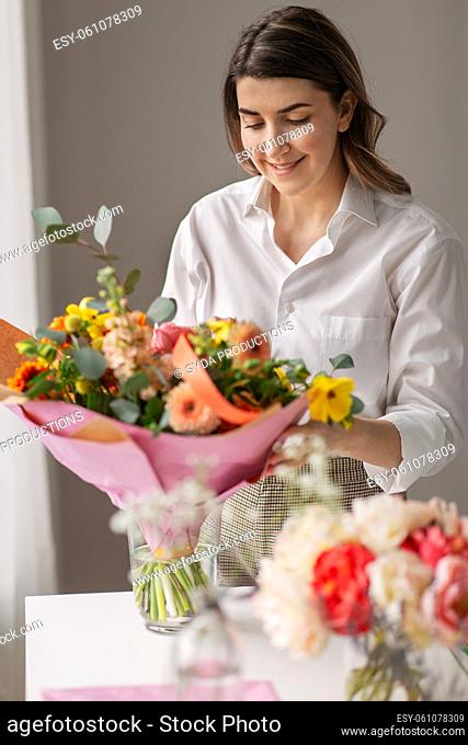 happy woman arranging flowers in vase at home