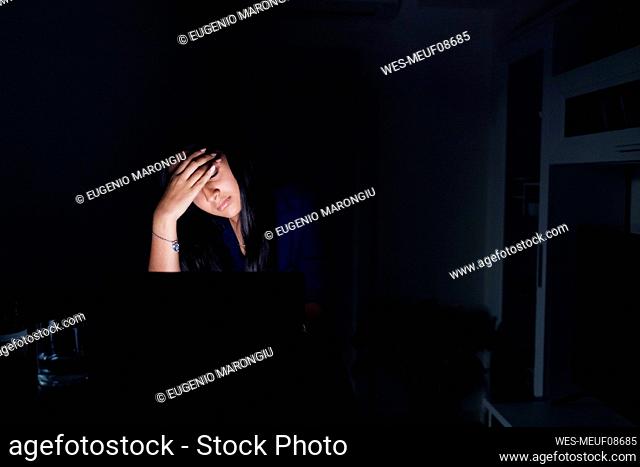 Tired young woman with laptop at home