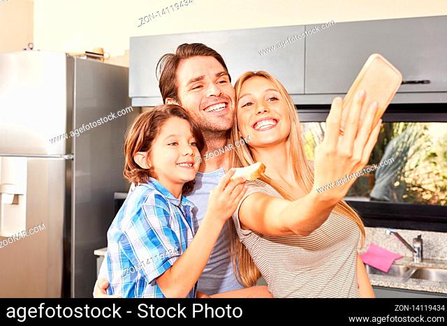 Glückliche Eltern und ihr Sohn machen in der Küche ein Selfie beim Frühstücken