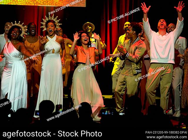 05 December 2023, Hamburg: Musical actress Mae Ann Jorolan (6th from left) as Meg and musical actor Benet Monteiro (3rd from right) as Hercules sing on stage at...